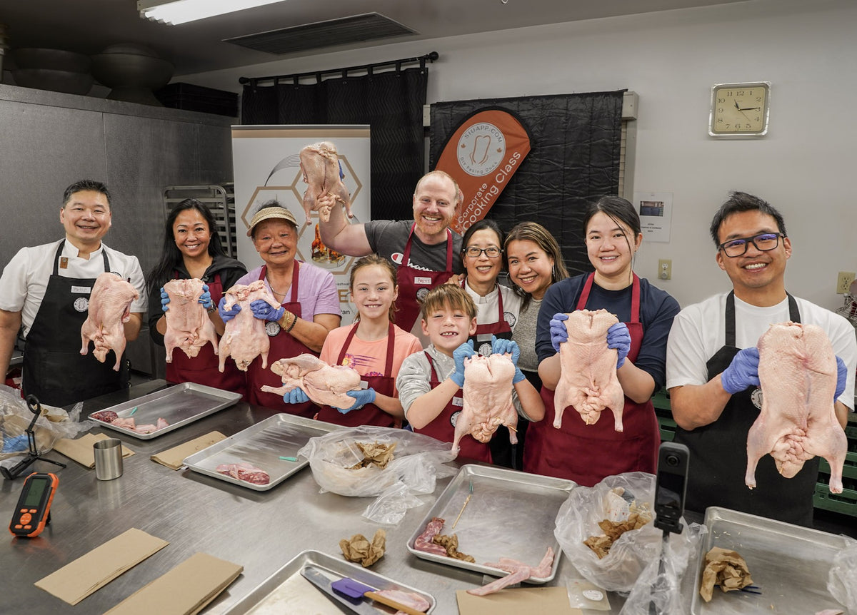 Chef Philip guiding a participant through hands-on duck preparation during a Peking duck cooking class.