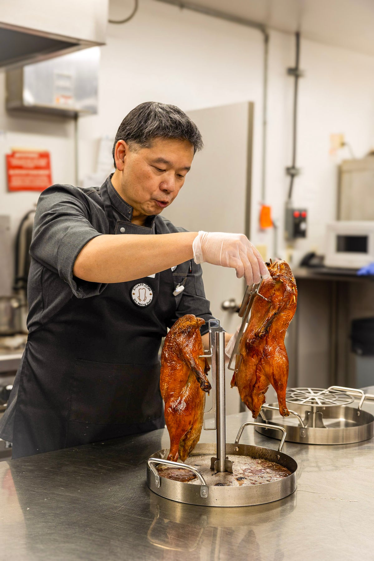 Chef Philip placing a duck on the UpRoaster hook during a Peking duck cooking demonstration.